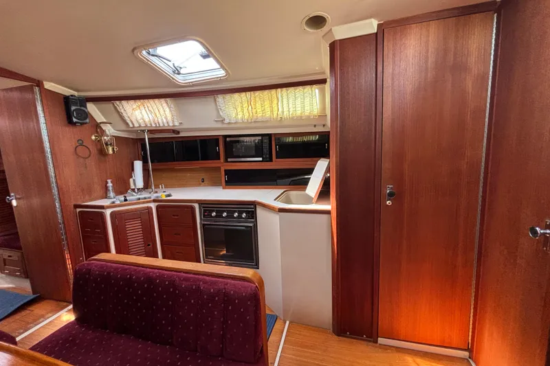 Interior of a 1990 Catalina 42 sailboat with wood paneling and kitchen area.