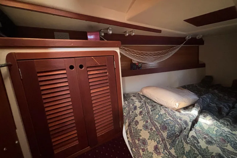 Cozy cabin interior of 1990 Catalina 42 sailboat with bed and wooden storage.