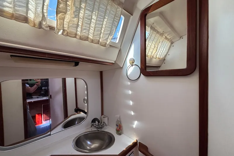 Bathroom interior of a 1990 Catalina 42 sailboat with mirrors and sink.