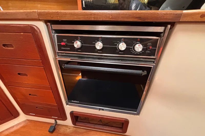 Stove and oven in 1990 Catalina 42 yacht kitchen, featuring wooden cabinetry.