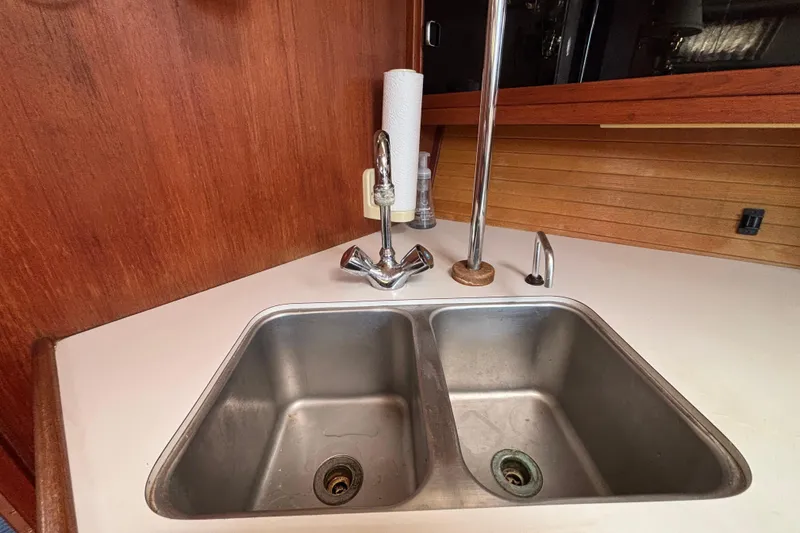 1990 Catalina 42 yacht kitchen sink with dual basins and wooden cabinetry.