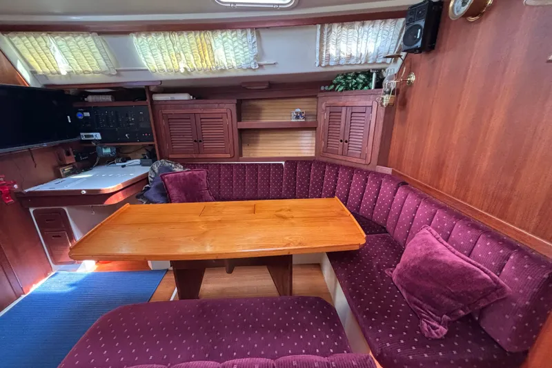 Interior of a 1990 Catalina 42 sailboat with plush seating and wooden table.