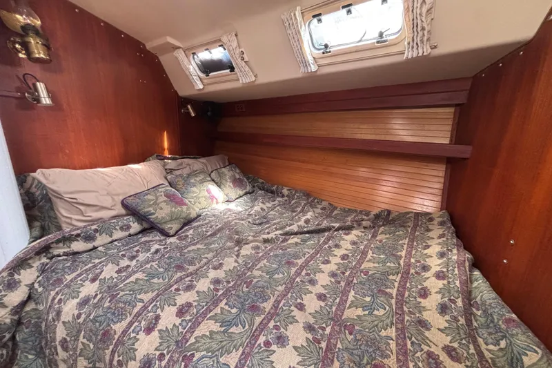 Cozy cabin interior of 1990 Catalina 42 sailboat with floral bedding and wood paneling.