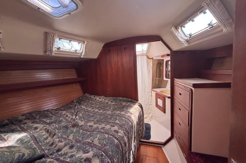 Cozy cabin interior of a 1990 Catalina 42 sailboat with wood paneling and bedding.