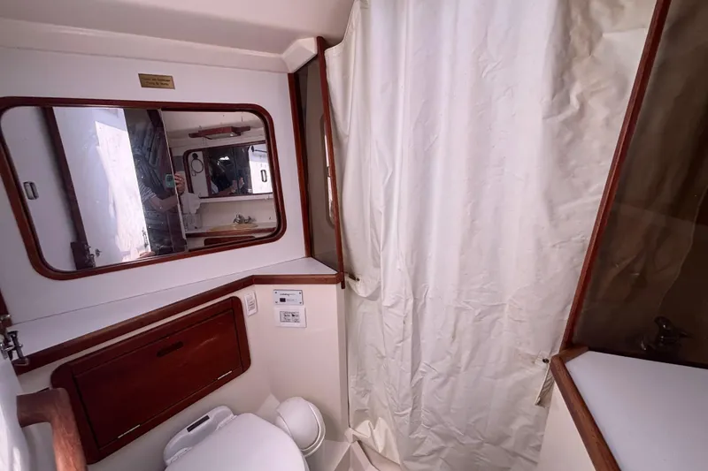 Bathroom interior of a 1990 Catalina 42 sailboat, featuring a mirror and shower curtain.
