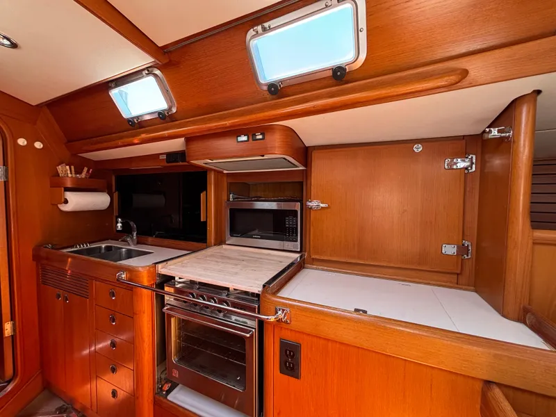 Nautor Swan 46 MK II 1994 yacht kitchen with wood cabinetry, oven, and sink.