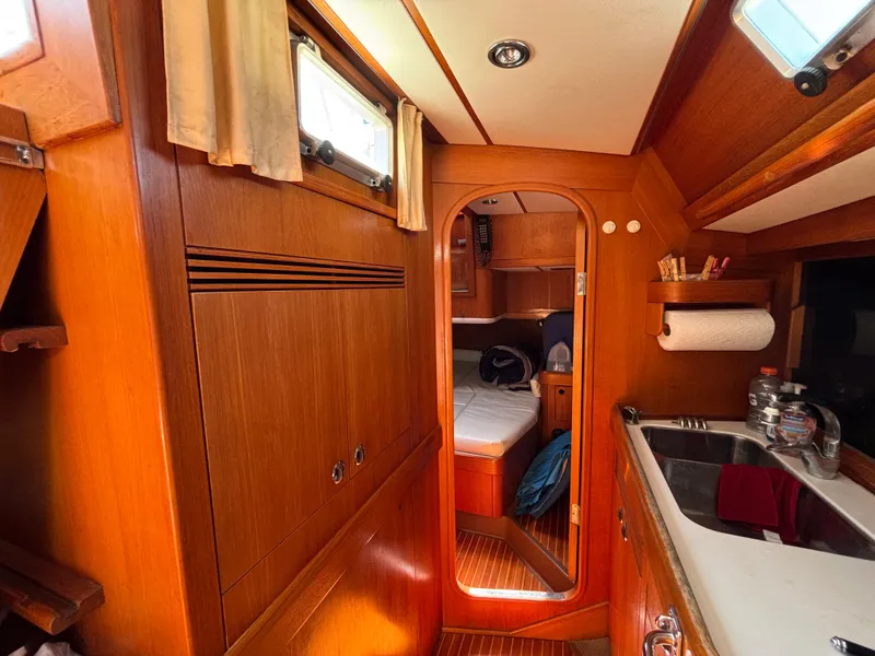 Interior of 1994 Nautor Swan 46 MK II yacht, featuring wood paneling and compact kitchen area.