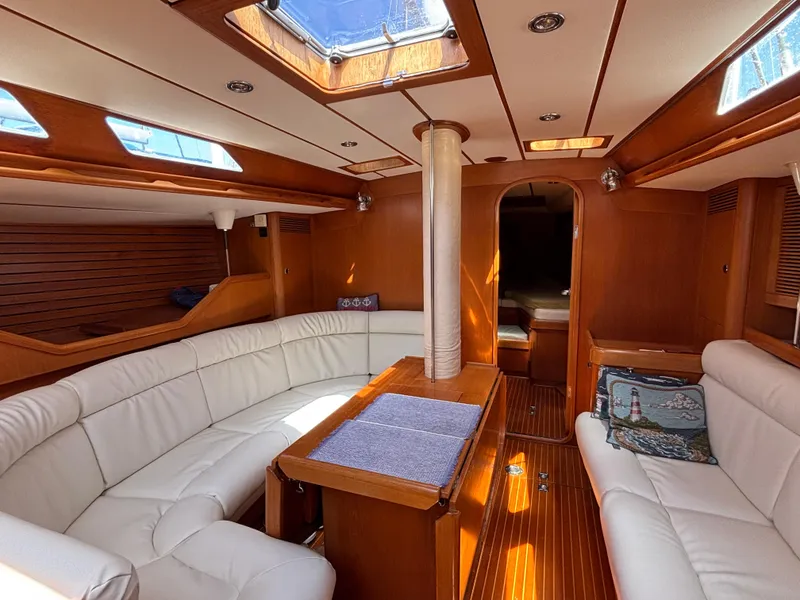 Luxurious interior of 1994 Nautor Swan 46 MK II yacht with white seating and wooden finishes.
