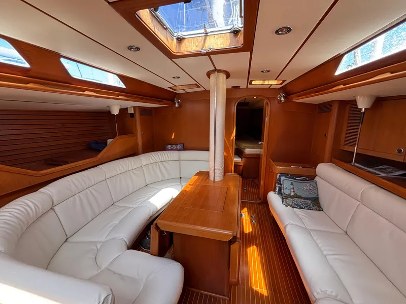 Luxurious interior of 1994 Nautor Swan 46 MK II yacht with white seating and wooden finishes.