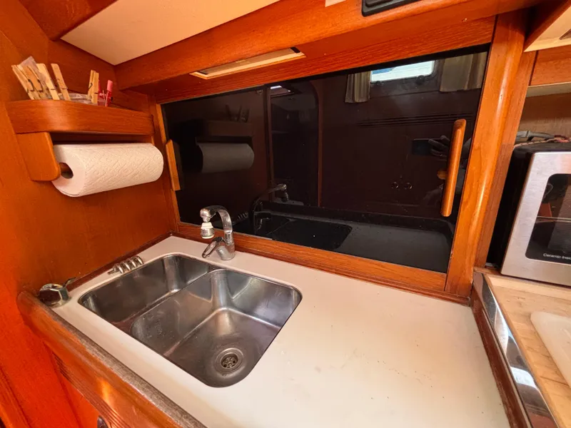 Galley sink area in 1994 Nautor Swan 46 MK II yacht, featuring wooden cabinetry and stainless steel sink.