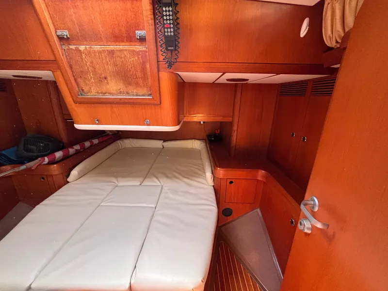 Interior cabin of 1994 Nautor Swan 46 MK II yacht with wooden finish and white bedding.