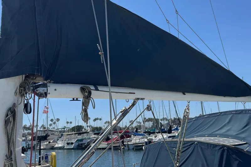 1989 Ericson Sloop sailboat with covered boom, docked in a marina under clear skies.