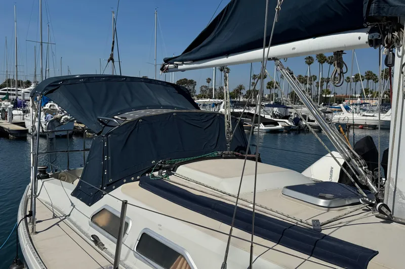 1989 Ericson Sloop sailboat docked at marina with blue canopy and rigging.