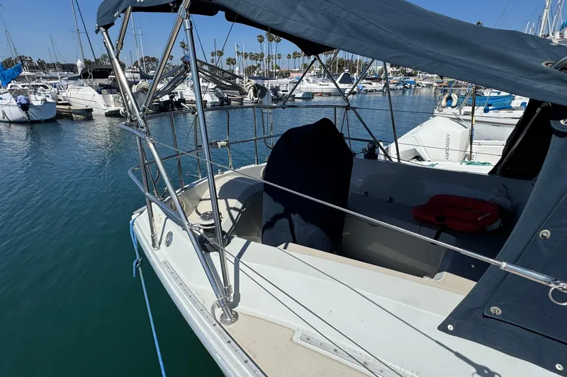 1989 Ericson Sloop sailboat docked in marina, featuring covered cockpit and clear blue water.