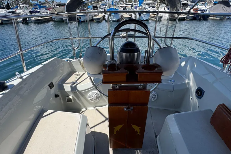 Cockpit of 1989 Ericson Sloop yacht with steering wheel and marina view.