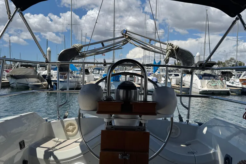 1989 Ericson Sloop sailboat cockpit view in marina with cloudy sky.
