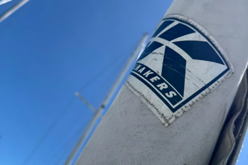 Close-up of a 1989 Ericson Sloop sail with a sailmaker's logo against a clear blue sky.