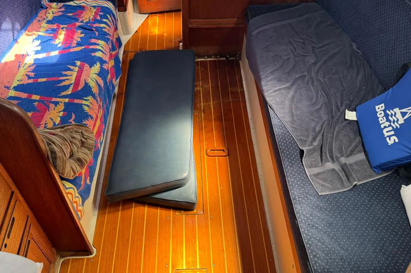 Interior of 1989 Ericson Sloop with colorful bedding and wooden flooring.