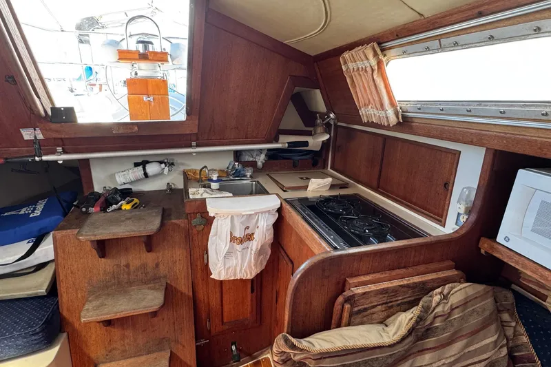 1989 Ericson Sloop interior with wooden cabinetry, compact kitchen, and nautical decor.