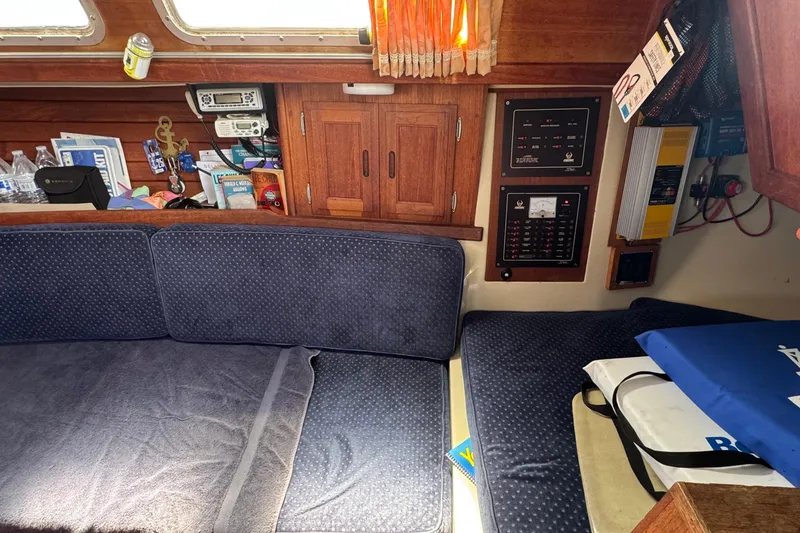 Interior of a 1989 Ericson Sloop sailboat with blue cushions and wooden cabinetry.