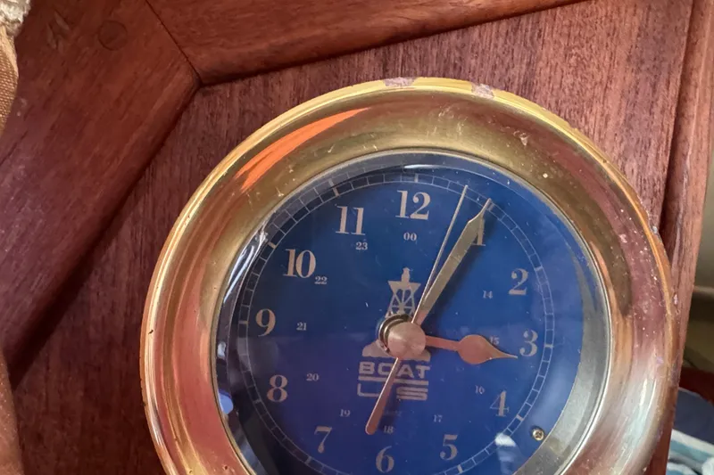 Brass nautical clock on 1989 Ericson Sloop with blue face and wooden frame.