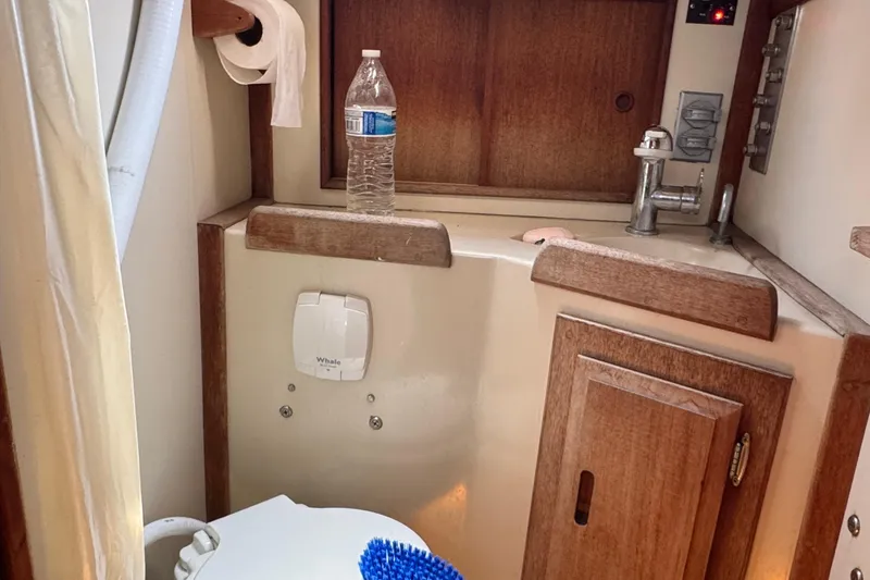 1989 Ericson Sloop bathroom with sink, toilet, and wooden cabinetry.