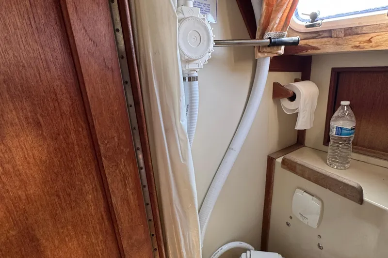 Interior of 1989 Ericson Sloop bathroom with pump, toilet paper, and water bottle.