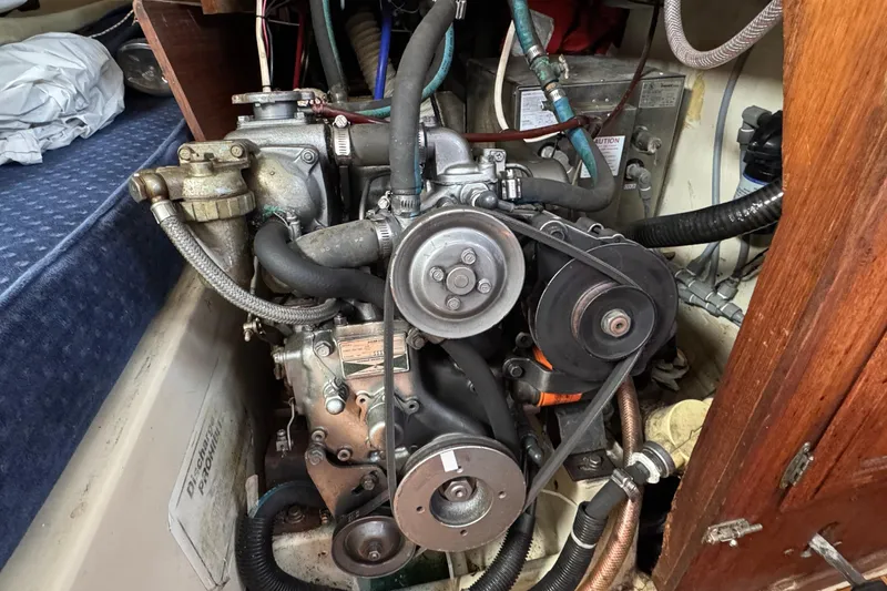 Engine compartment of a 1989 Ericson Sloop sailboat, showcasing mechanical components and hoses.
