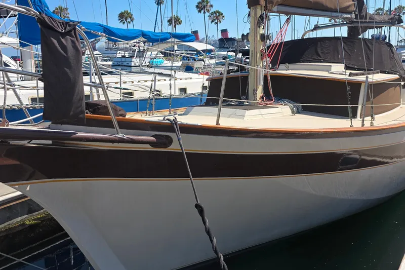 1978 Islander Freeport 41 sailboat docked at marina with blue tarps and palm trees.