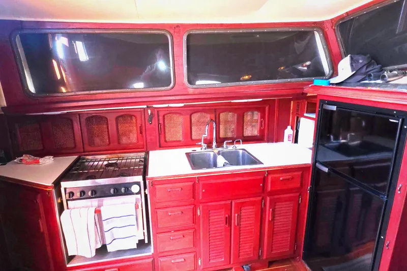 1978 Islander Freeport 41 yacht kitchen with wooden cabinets, stove, sink, and refrigerator.