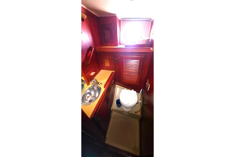 1978 Islander Freeport 41 yacht bathroom with sink, toilet, and wooden cabinetry.