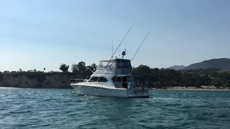 2004 Riviera 47 Flybridge yacht on calm waters near a scenic coastline.