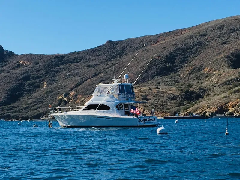 2004 Riviera 47 Flybridge yacht anchored in scenic coastal waters.