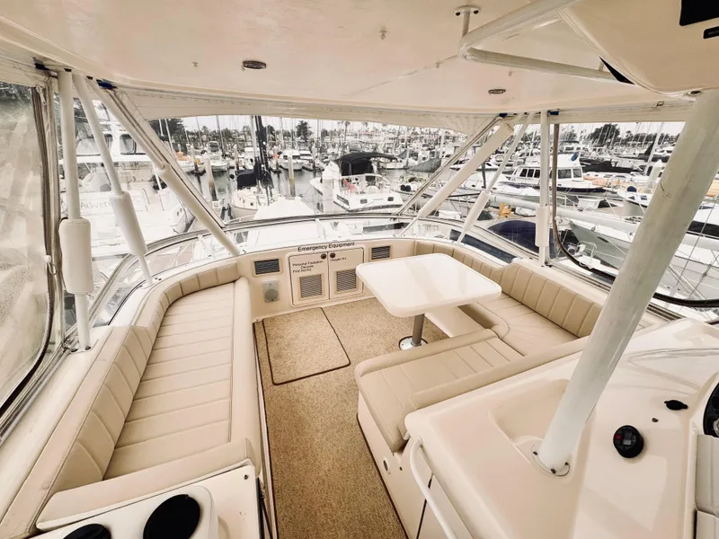 2004 Riviera 47 Flybridge interior with beige seating, table, and marina view.