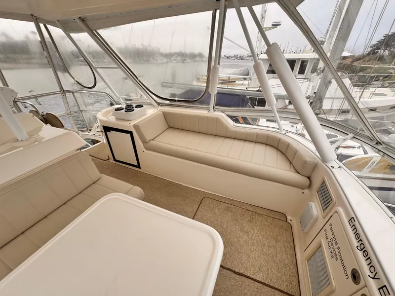 2004 Riviera 47 Flybridge interior with beige seating and table, overlooking marina.