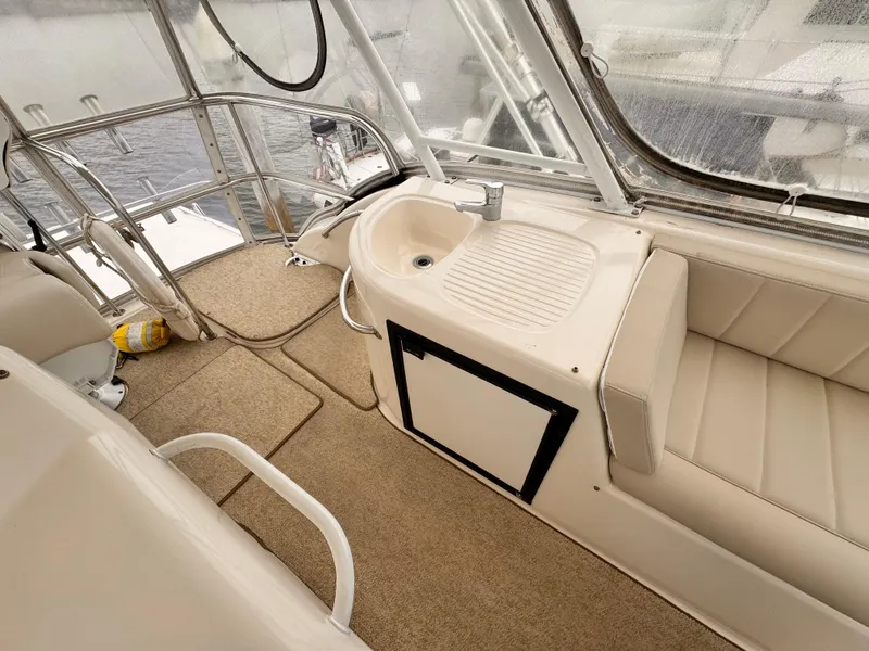 2004 Riviera 47 Flybridge interior with beige seating, sink, and carpeted flooring.