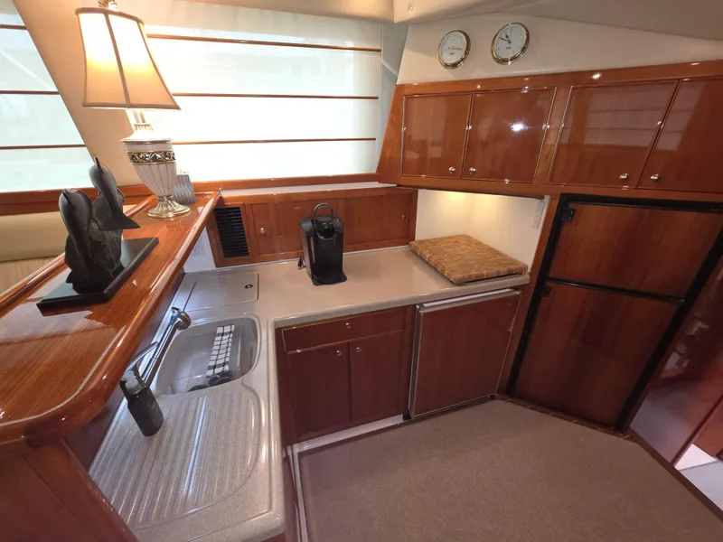 Luxurious 2004 Riviera 47 Flybridge yacht kitchen with wooden cabinetry and modern appliances.