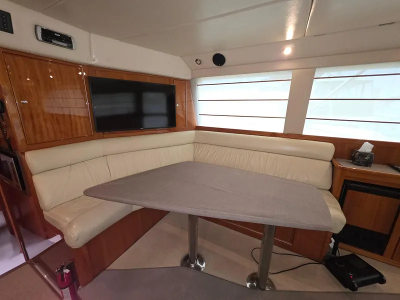 Interior of 2004 Riviera 47 Flybridge yacht with beige seating and wooden accents.