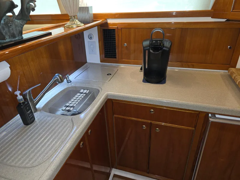 2004 Riviera 47 Flybridge kitchen with wooden cabinets, sink, and coffee maker.