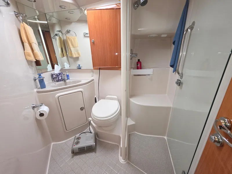 Bathroom interior of 2004 Riviera 47 Flybridge yacht, featuring shower, toilet, and storage.
