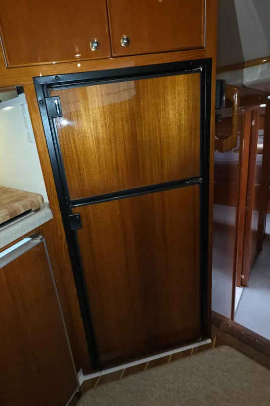 Wooden interior of 2004 Riviera 47 Flybridge yacht, featuring a built-in refrigerator.