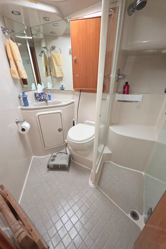 Bathroom interior of 2004 Riviera 47 Flybridge yacht, featuring shower and wooden cabinetry.