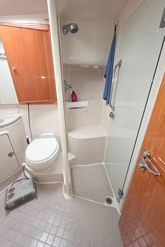 2004 Riviera 47 Flybridge bathroom with shower, toilet, and wooden cabinetry.