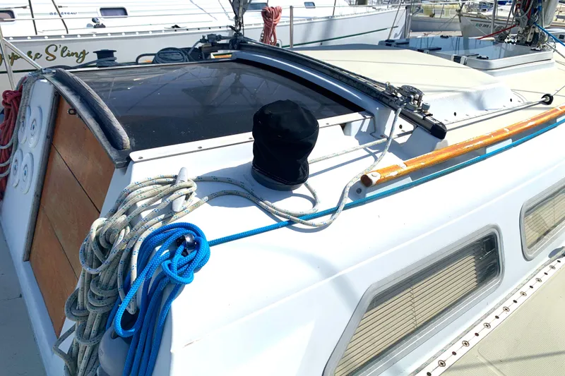 1984 Ericson 30 Plus sailboat deck with ropes and hatch, docked in a marina.