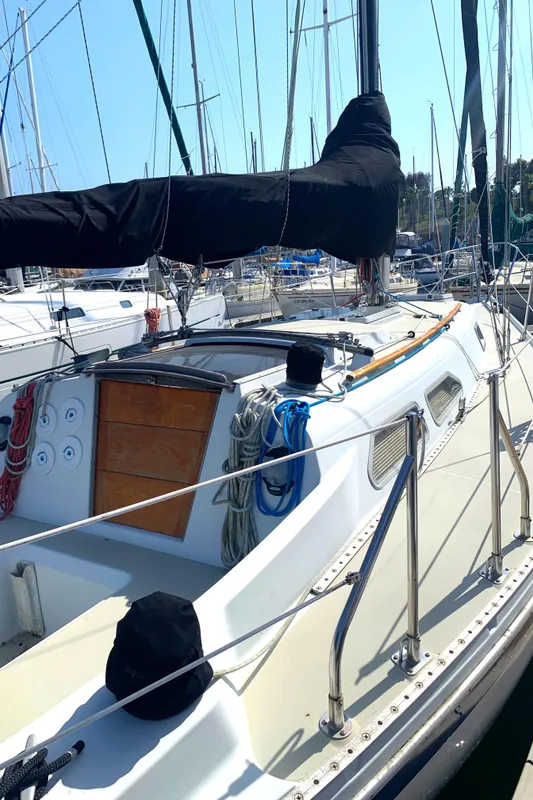 1984 Ericson 30 Plus sailboat docked at marina, featuring covered boom and tidy deck.