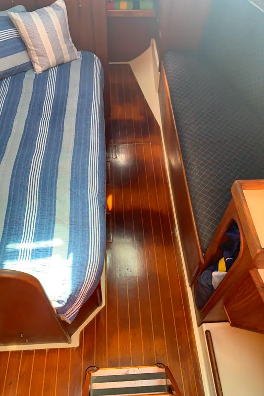 1984 Ericson 30 Plus interior with striped bedding and polished wooden flooring.