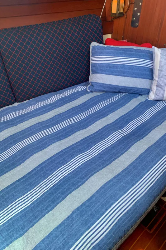 Cozy cabin interior of 1984 Ericson 30 Plus sailboat with striped bedding.