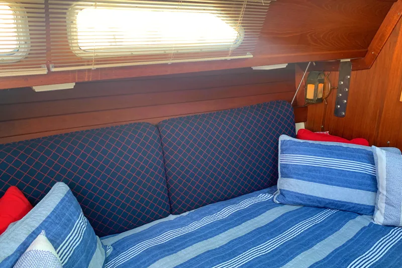 Cozy cabin interior of 1984 Ericson 30 Plus sailboat with striped bedding and cushions.