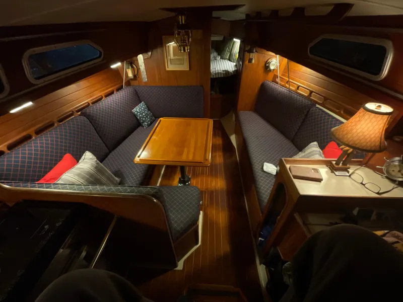 Cozy interior of a 1984 Ericson 30 Plus sailboat with wood paneling and cushioned seating.