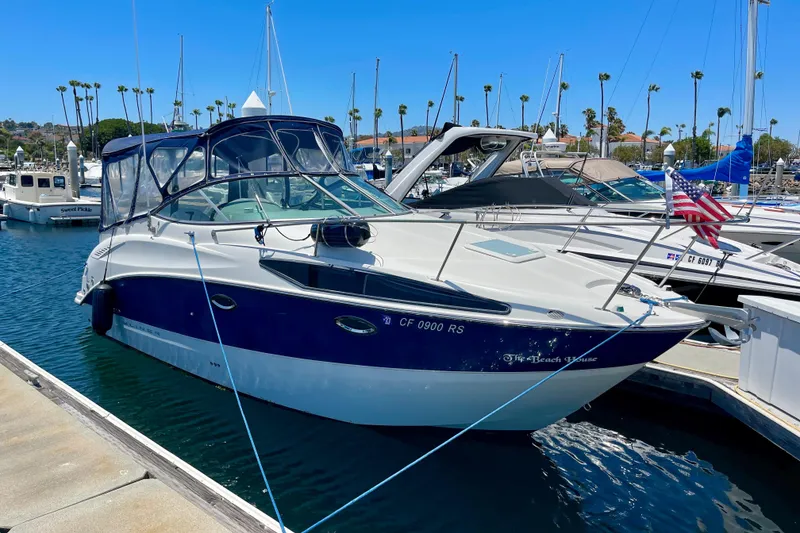 2008 Bayliner 265 boat docked in a marina, clear blue sky background.
